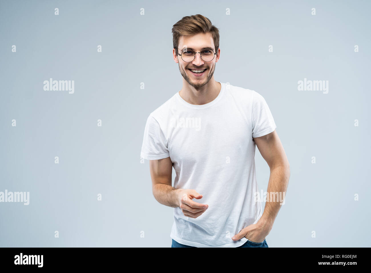 Ritratto di bel giovane con sorriso raggiante su sfondo grigio. Foto Stock