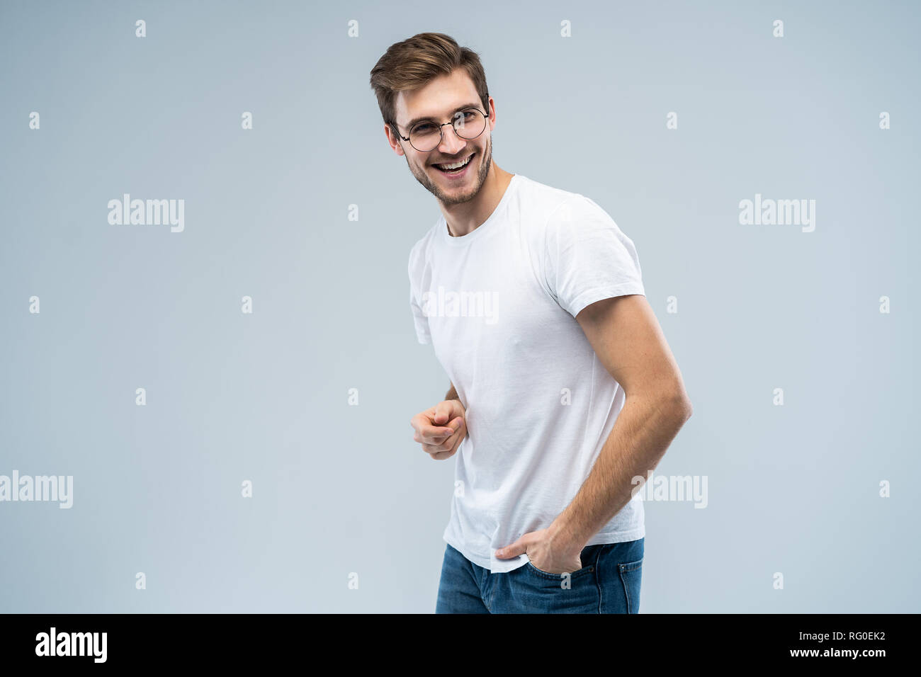 Ritratto di bel giovane con sorriso raggiante su sfondo grigio. Foto Stock