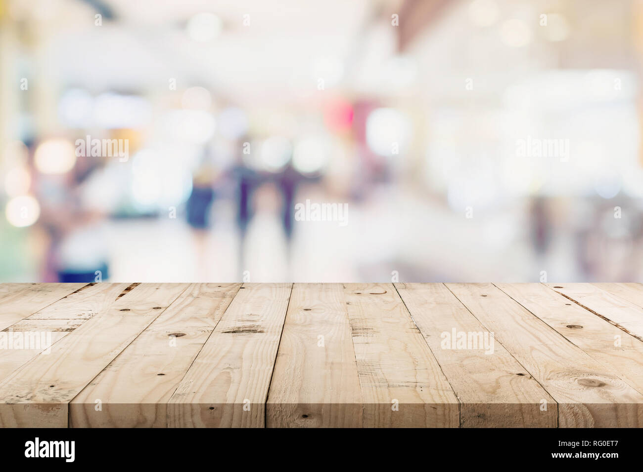 Svuotare tavolo di legno e gente di shopping in department store. Defocalizzata blur sullo sfondo, display montage per prodotto con copia spazio. Foto Stock