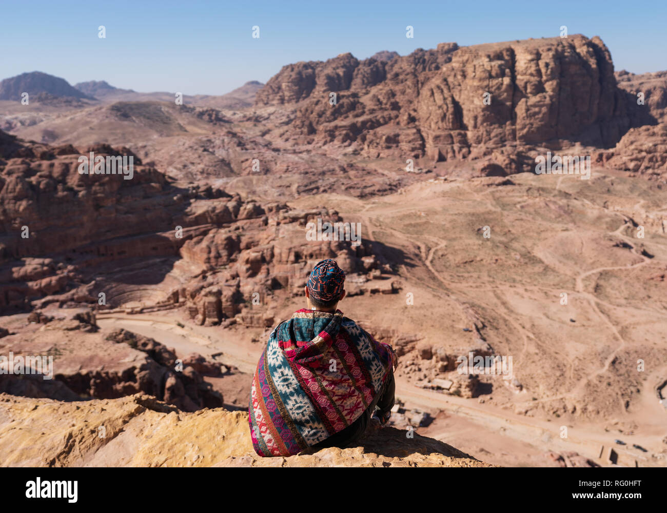 Viaggiatore seduto sul bordo della scogliera di montagna, a Wadi Rum desert in Giordania. Lo stile di vita di viaggi e di avventura e di viaggio Foto Stock