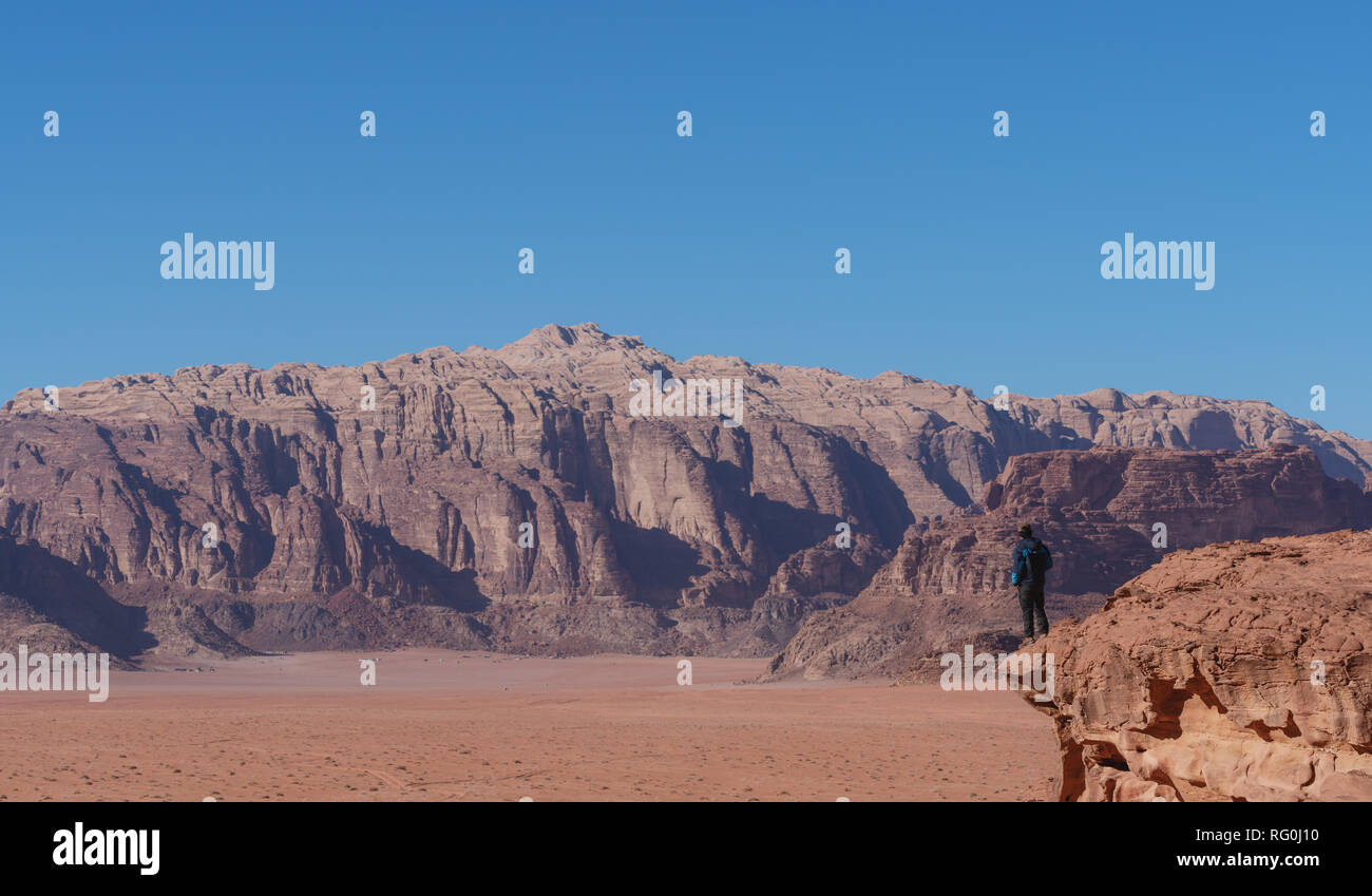 Traveler in piedi sul bordo della scogliera di montagna, a Wadi Rum desert in Giordania. Lo stile di vita di viaggi e di avventura e di viaggio Foto Stock