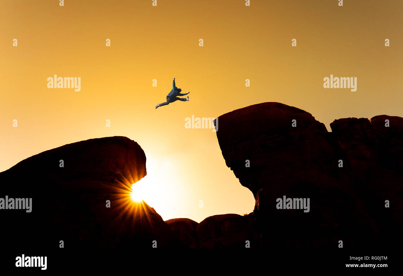 Sfida, rischio e concetto di libertà. La silhouette di un uomo saltando su strapiombo attraversando cliff Foto Stock