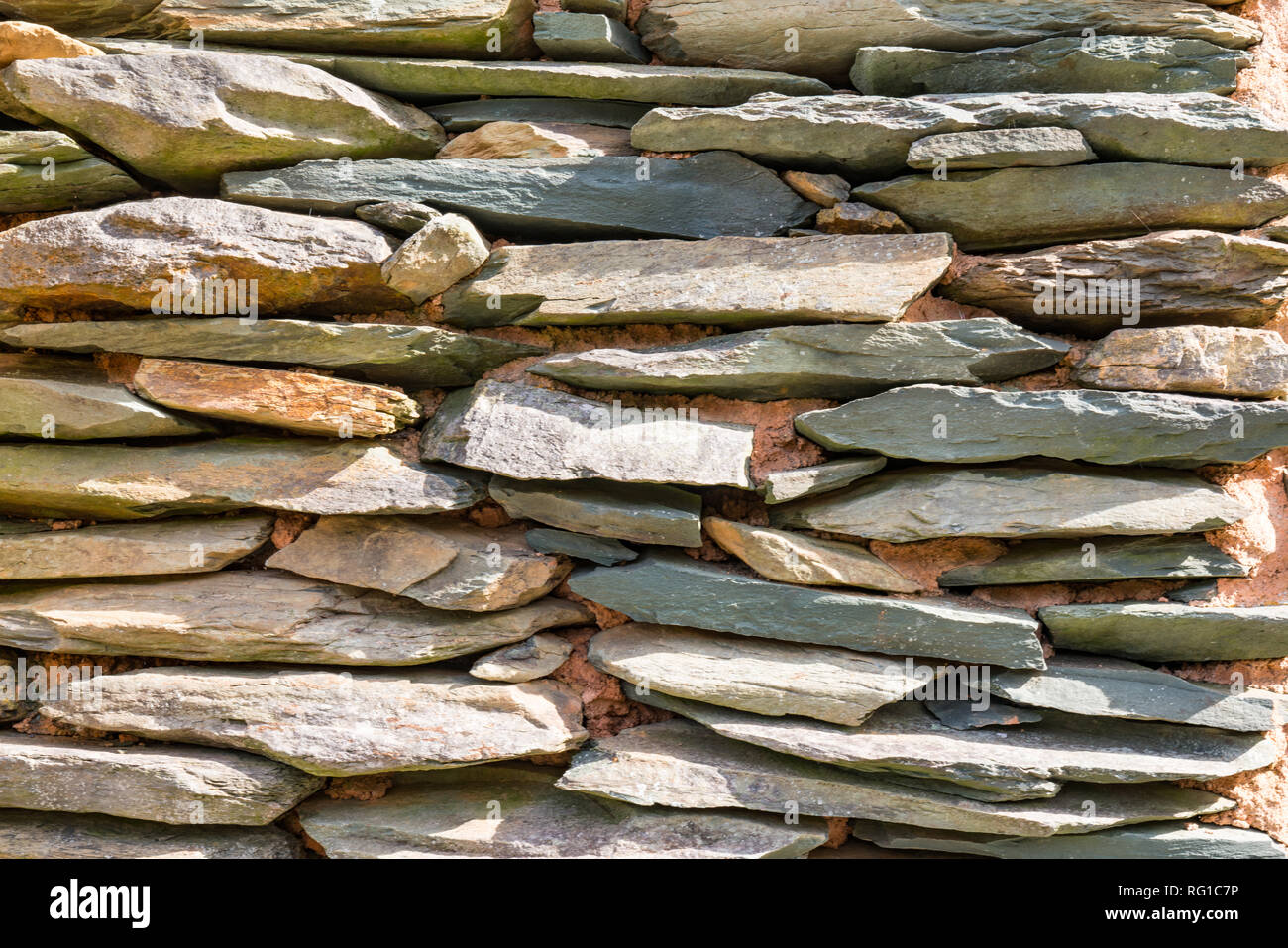 Pietra ardesia impilati su un rustico di muro di pietra Foto Stock