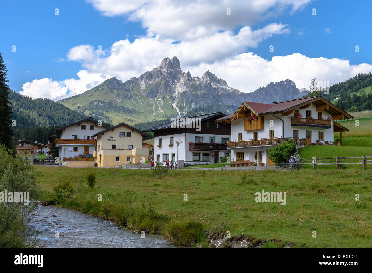 Persone escursionismo al di fuori di un Chalet al di sotto di un picco di montagna delle Alpi in Austria durante il giorno Foto Stock
