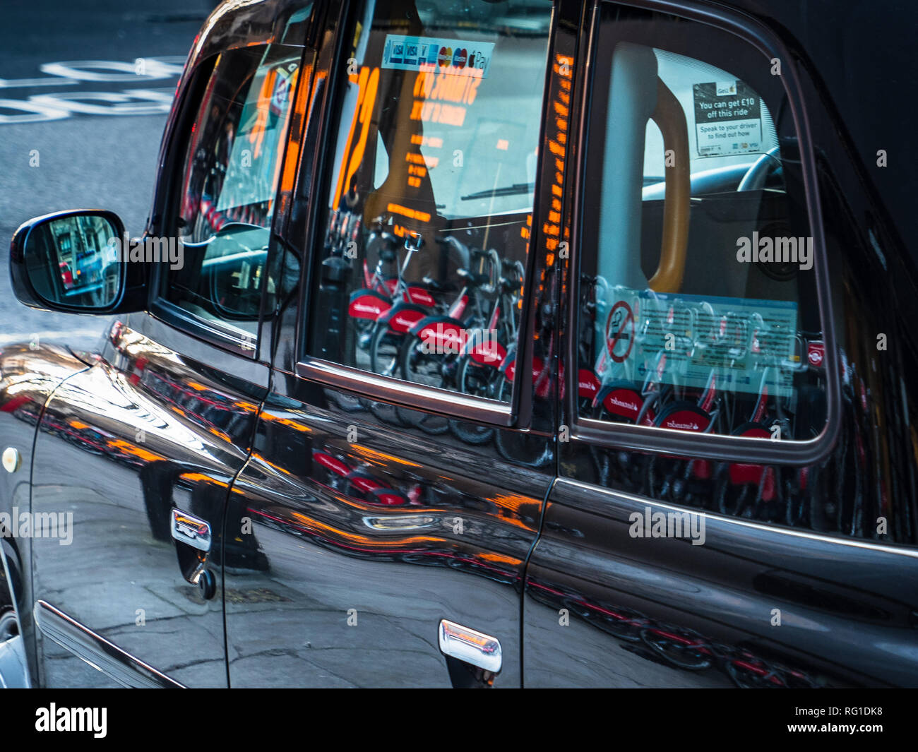 Taxi di Londra, London Black Cab - luci di strada e biciclette a noleggio riflessa dal lato di un taxi a Londra nel centro di Londra Foto Stock