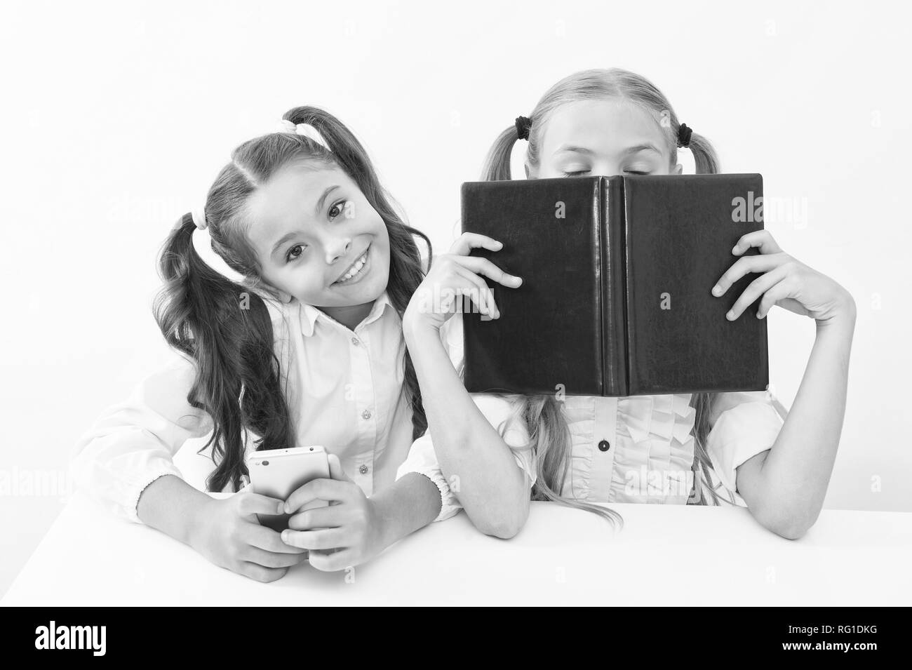 Vecchia scuola contro le moderne. Schoolgirl tenere premuto Telefono cellulare smartphone moderno mentre il suo amico godere vecchio libro come dati analogici di storage. La tecnologia contro l'esperienza. Nuova generazione di istanze educative. Foto Stock
