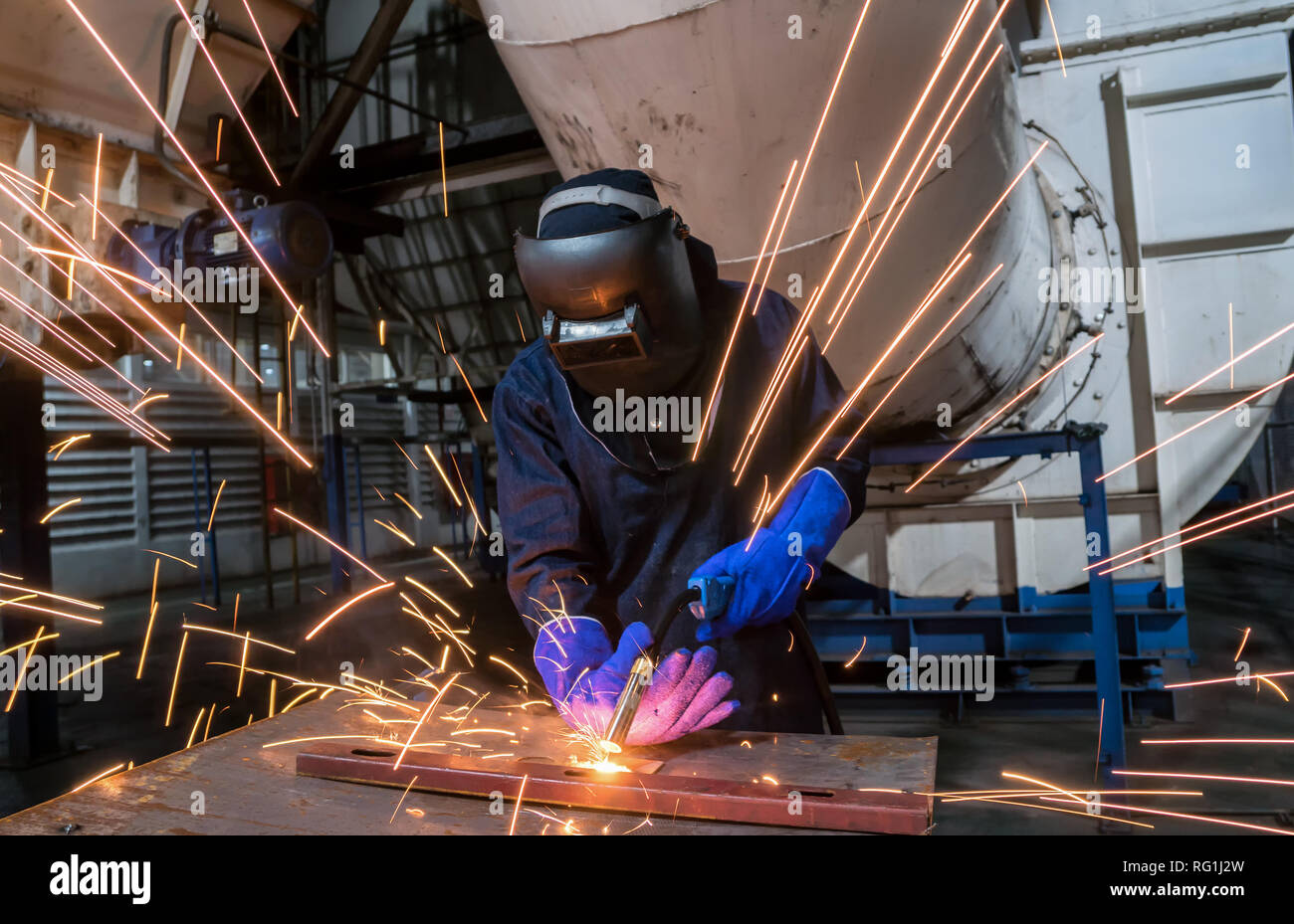 Il lavoratore industriale sta saldando parti di acciaio di riparazione in fabbrica Foto Stock