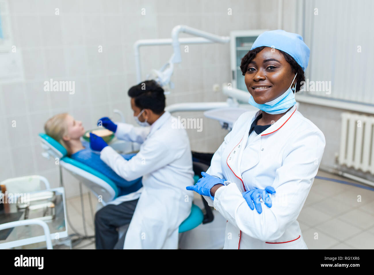 Ritratto di femmina nera dentista in studio dentistico. Ella in piedi presso il suo ufficio e ha uno splendido sorriso. Moderne attrezzature mediche Foto Stock