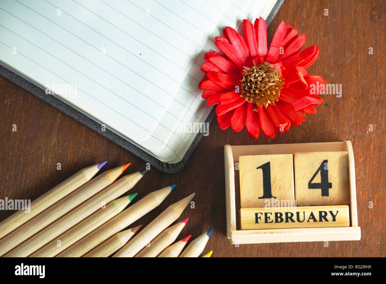 Legno Topview Calendario del 14 febbraio e matite e fiori e diario libro sul tavolo di legno, il concetto di amore. Foto Stock