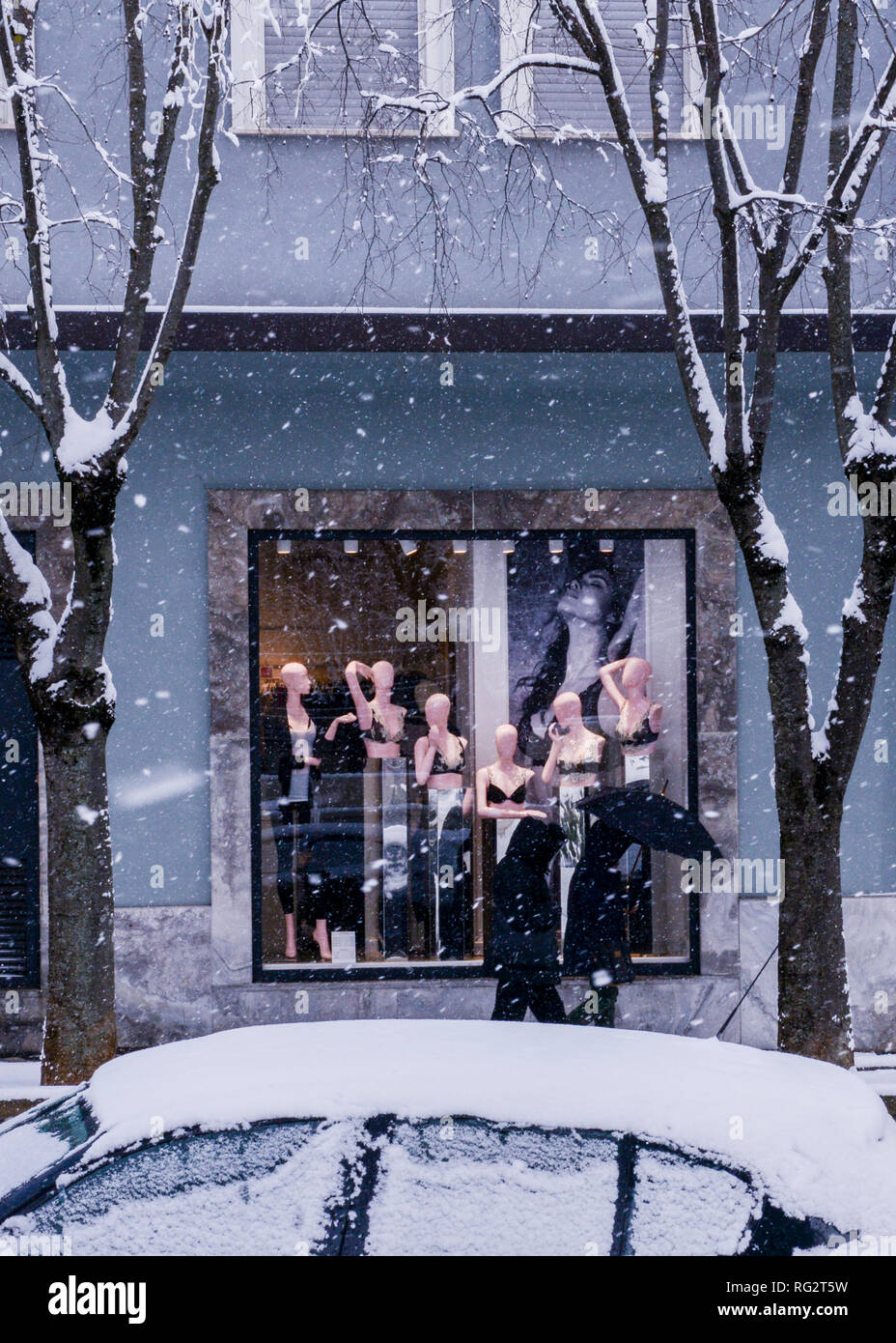Due persone che camminano passato vetrina con manichino display, durante la tempesta di neve, Avezzano, regione Abruzzo, Italia, Europa Foto Stock