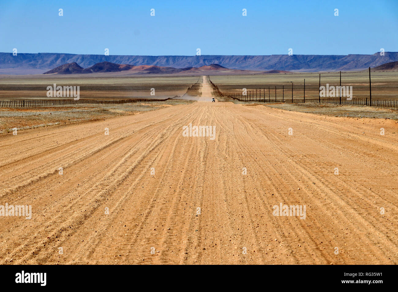 Infinite lungo la strada attraverso l'erba steppe con montagne - Namibia Africa Foto Stock