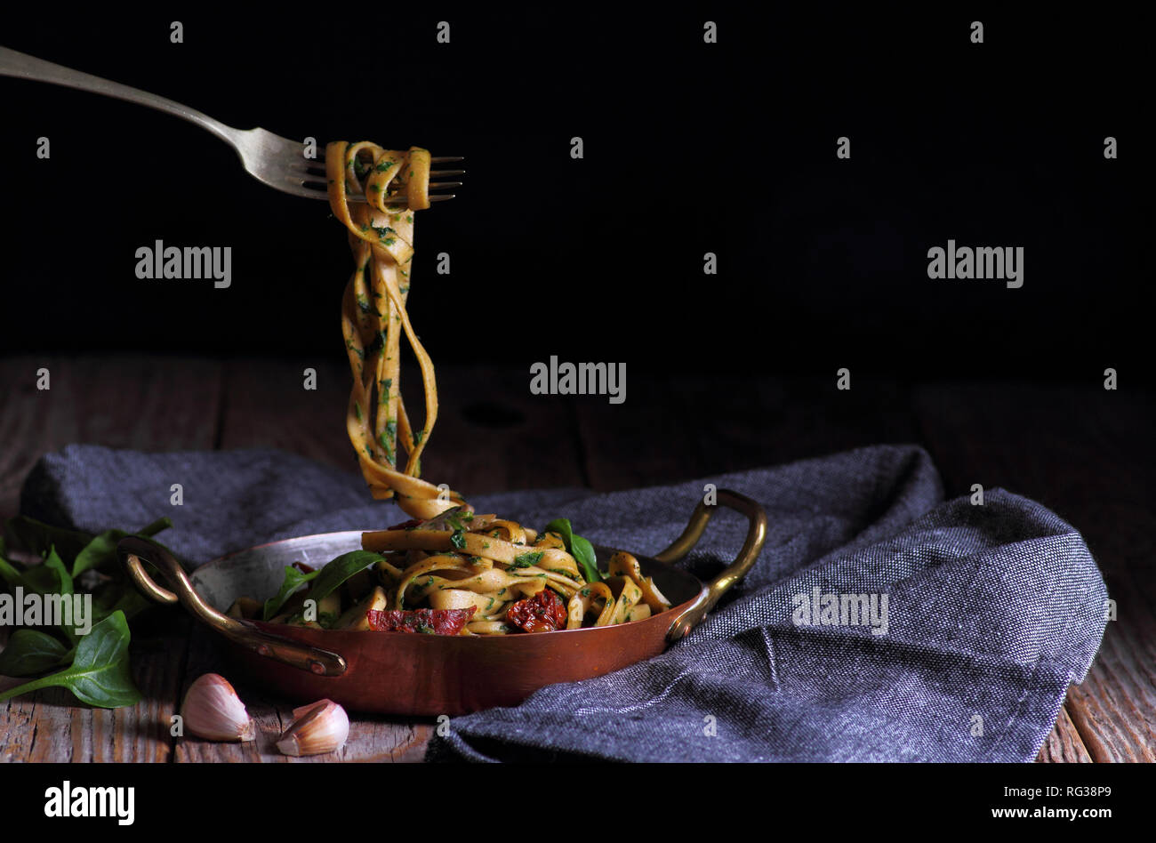 Spaghetti con spinaci e pomodori secchi. Forcella con spaghetti al di sopra della piastra. Foto Stock