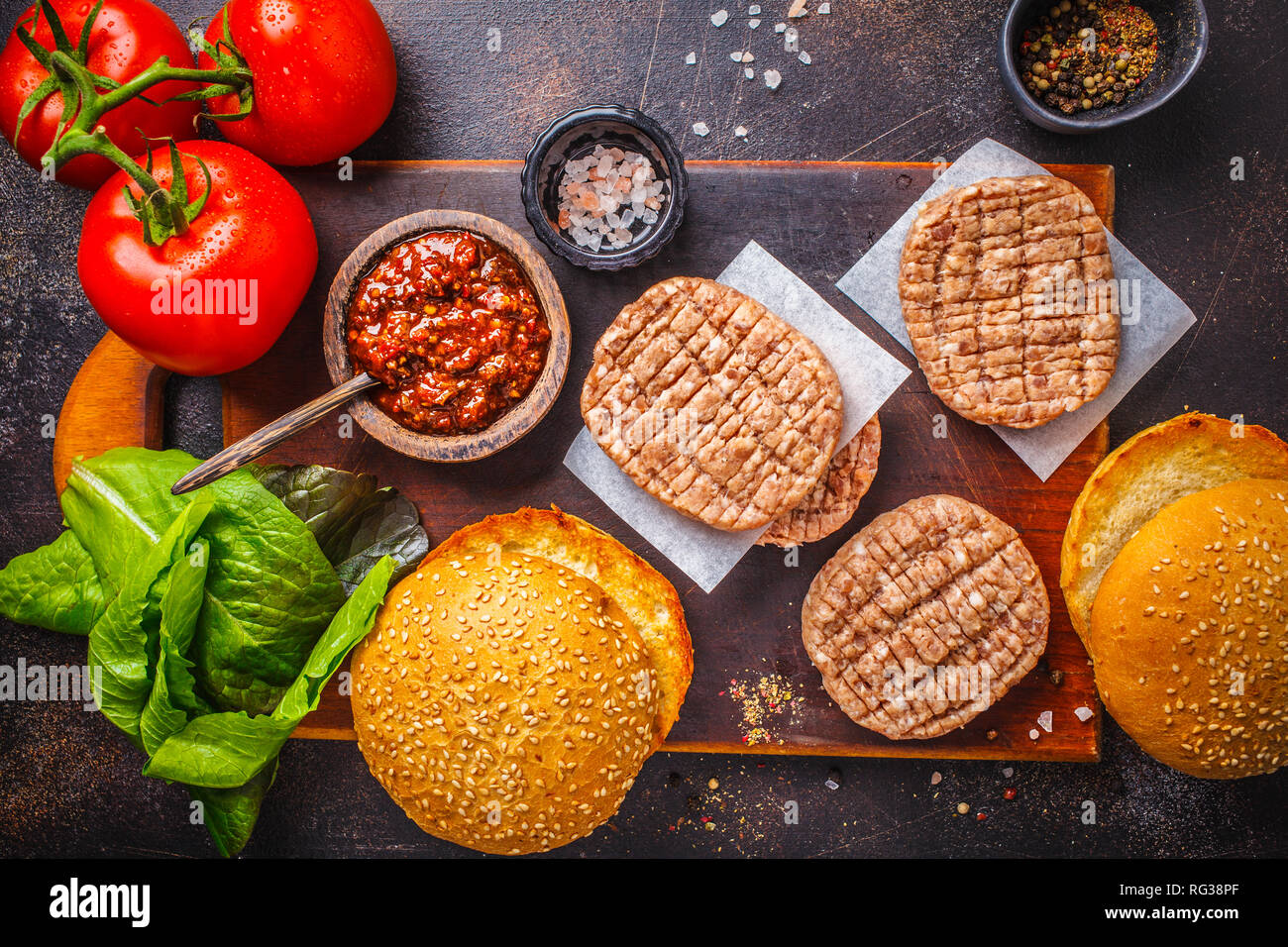 Ingredienti per gli hamburger di carne con verdure e coleslaw su uno sfondo scuro, vista dall'alto, copia dello spazio. Foto Stock