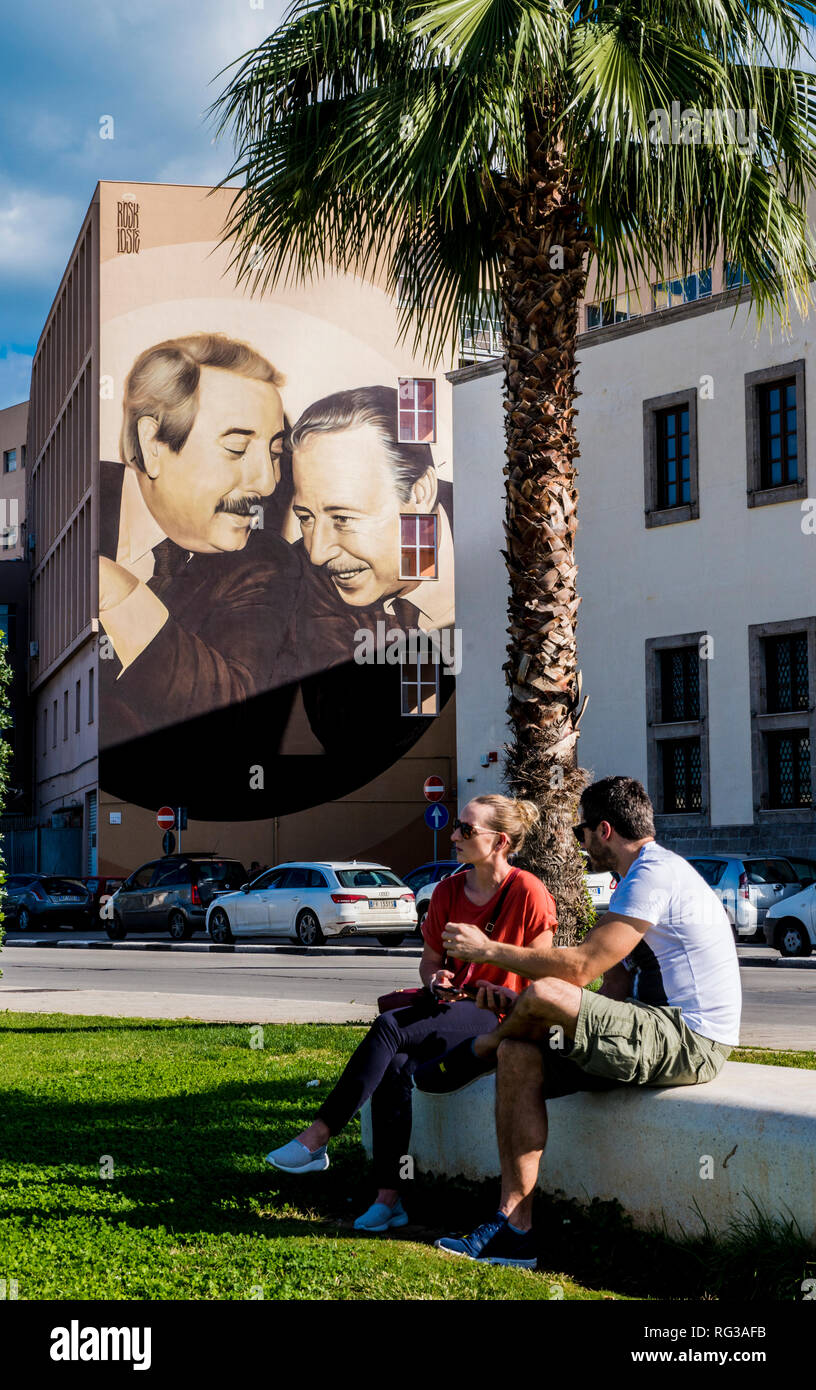 Giovane seduto su un banco di lavoro, murale in background che mostra famoso giudici Giovanni Falcone e Paolo Borsellino, della città di Palermo, Sicilia, Italia, Europa Foto Stock