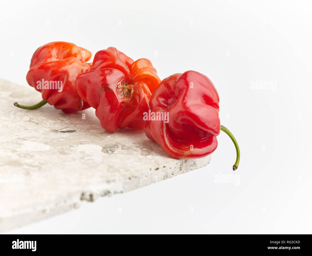 Scotch Bonnet pepe e chiazze di superficie in marmo contro la luce dello sfondo. Fotografia di cibo Foto Stock