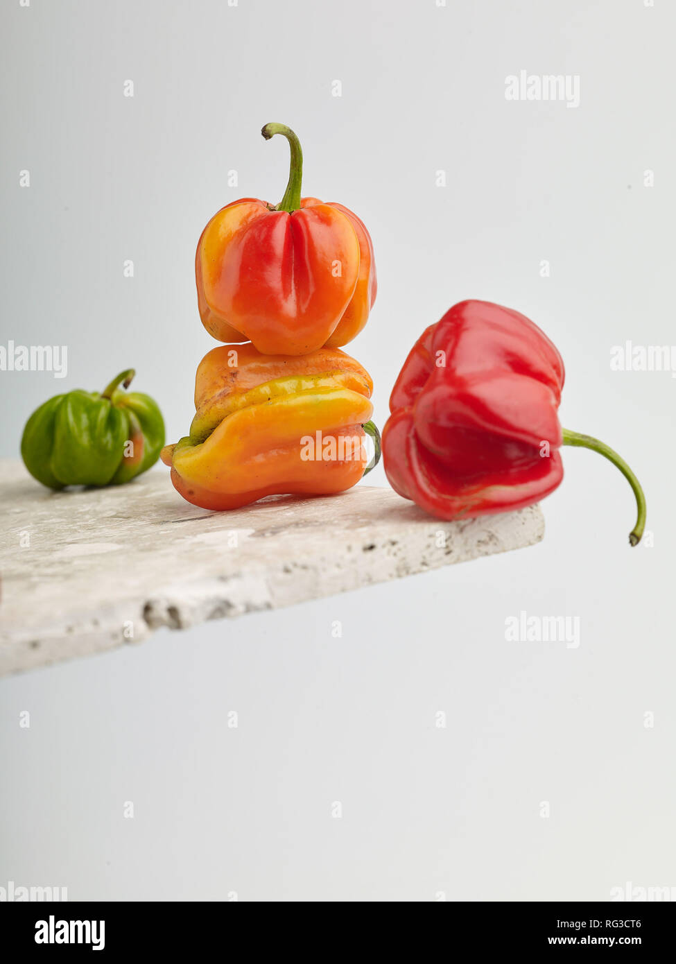 Scotch Bonnet pepe e chiazze di superficie in marmo contro la luce dello sfondo. Fotografia di cibo Foto Stock