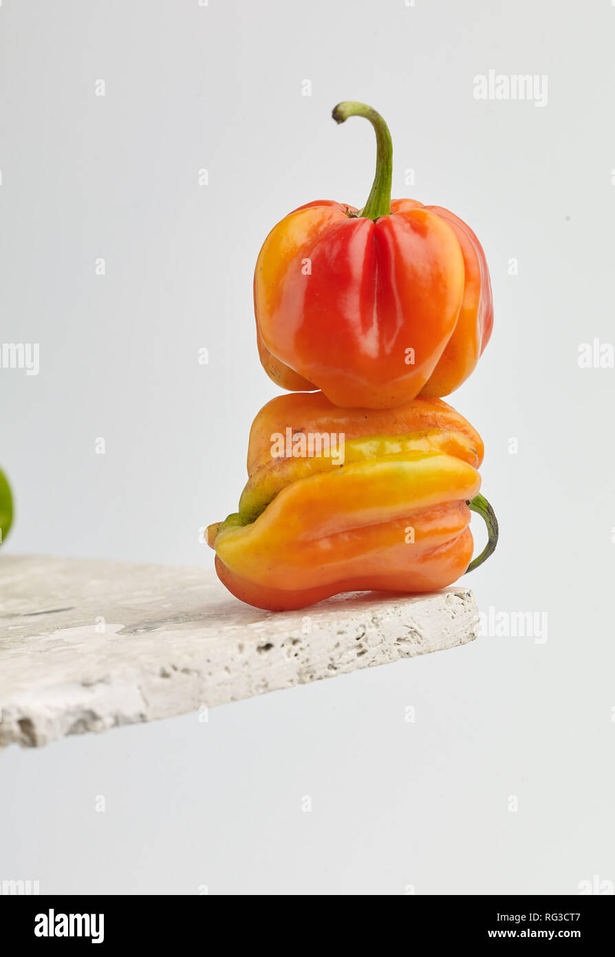 Scotch Bonnet pepe e chiazze di superficie in marmo contro la luce dello sfondo. Fotografia di cibo Foto Stock