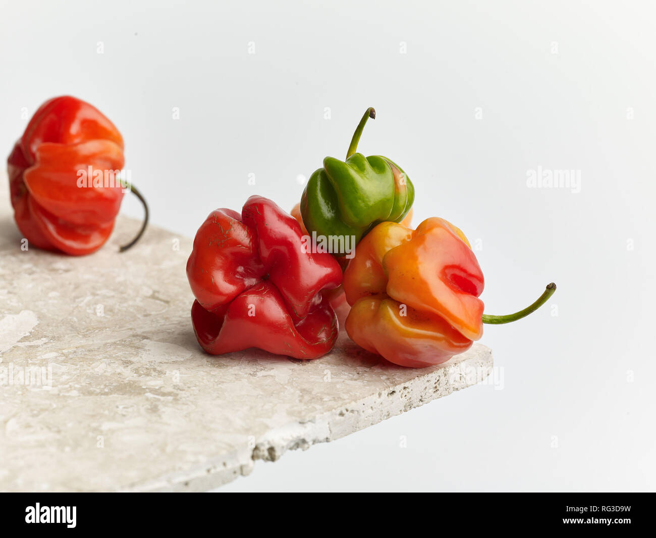 Scotch Bonnet pepe e chiazze di superficie in marmo contro la luce dello sfondo. Fotografia di cibo Foto Stock