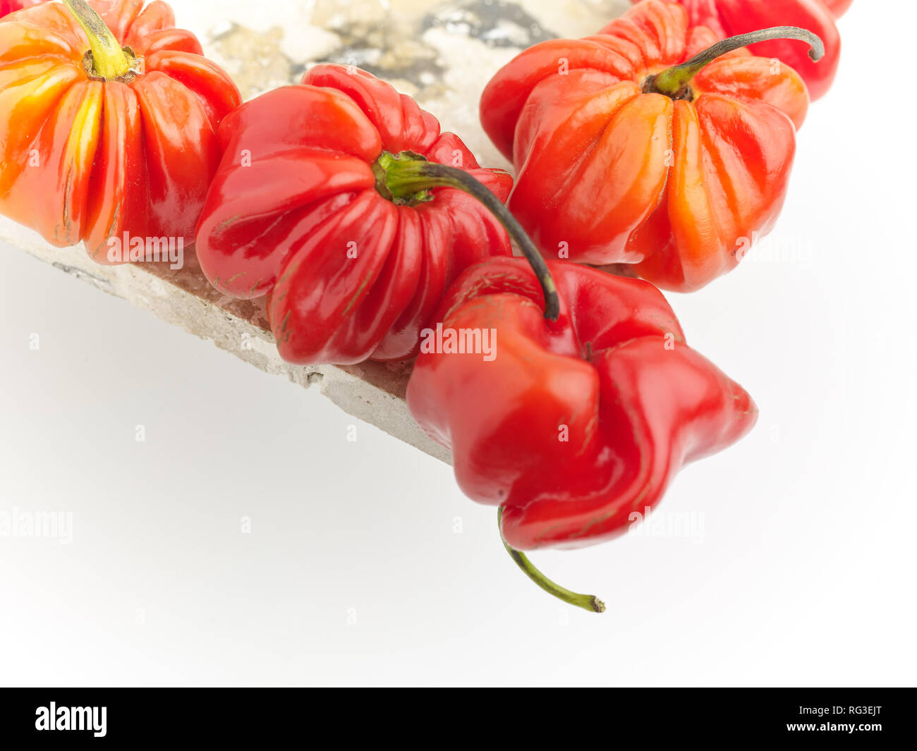 Scotch Bonnet pepe e chiazze di superficie in marmo contro la luce dello sfondo. Fotografia di cibo Foto Stock