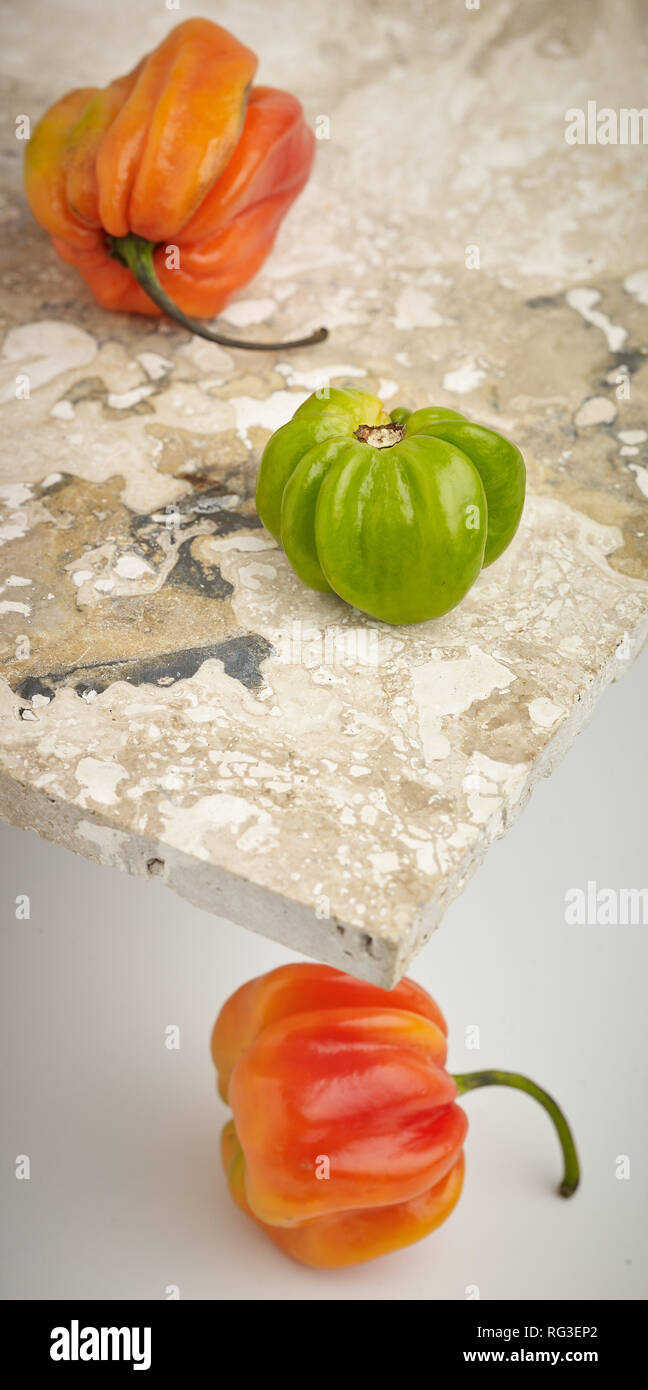 Scotch Bonnet pepe e chiazze di superficie in marmo contro la luce dello sfondo. Fotografia di cibo Foto Stock