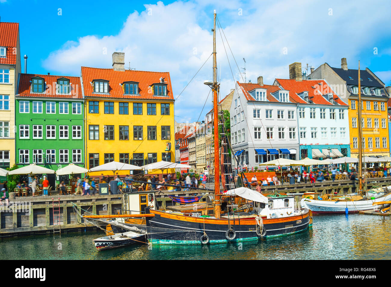 Scenic Nyhavn visualizzare con barche da embankment nel sole splendente, gente che passeggia e seduta in ristoranti, Copenhagen, Danimarca Foto Stock