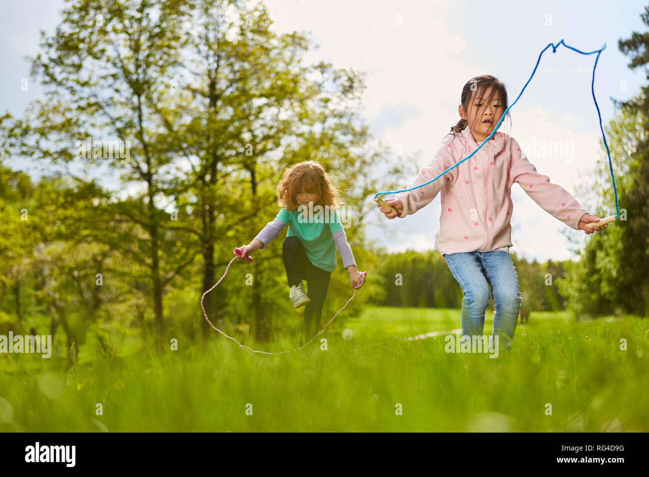 Due ragazze in Salto con la corda su un prato nel parco di vacanze estive Foto Stock