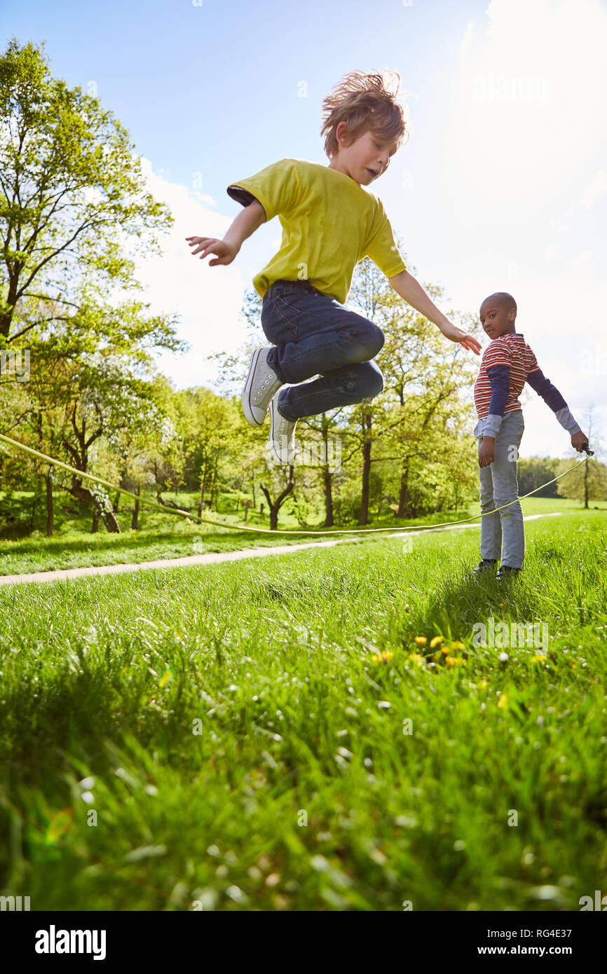 Due ragazzi in Salto con la corda insieme nel giardino in estate vacanze Foto Stock