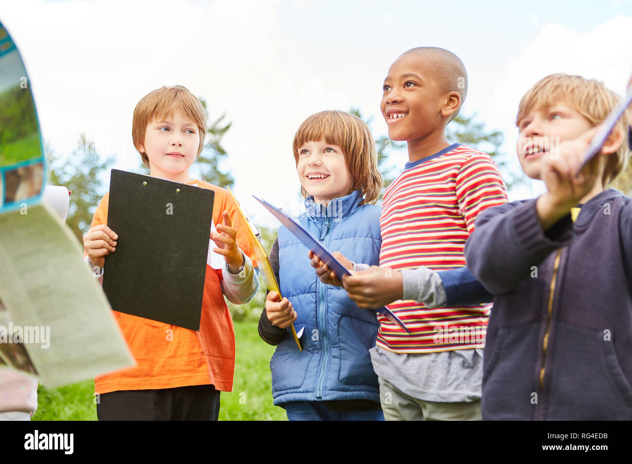 Un gruppo di ragazzi con appunti sulla caccia al tesoro in natura alla festa di compleanno di bambini Foto Stock
