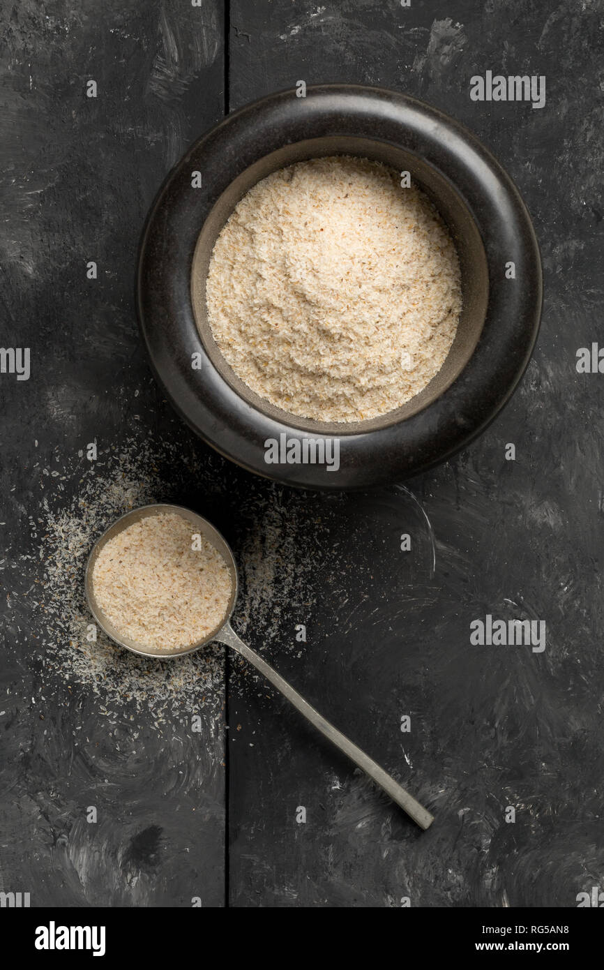 Accumulo di pula di psillio anche chiamato isabgol in mortaio e cucchiaio in metallo nero su sfondo tabella. Psillio lolla anche chiamato isabgol è fibra derivata da Foto Stock