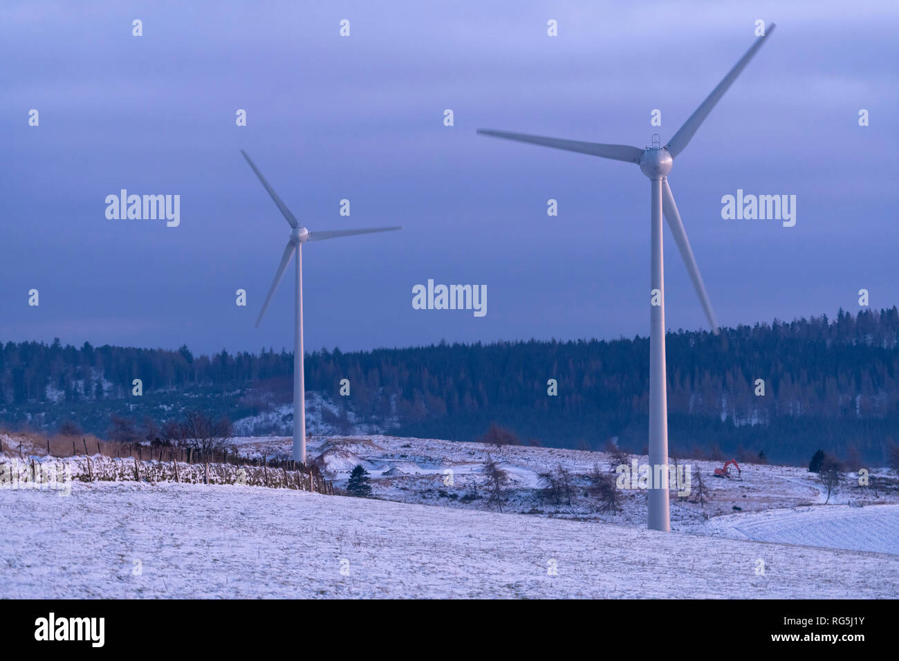 Le turbine eoliche sotto il chiaro di luna in un paesaggio invernale Foto Stock