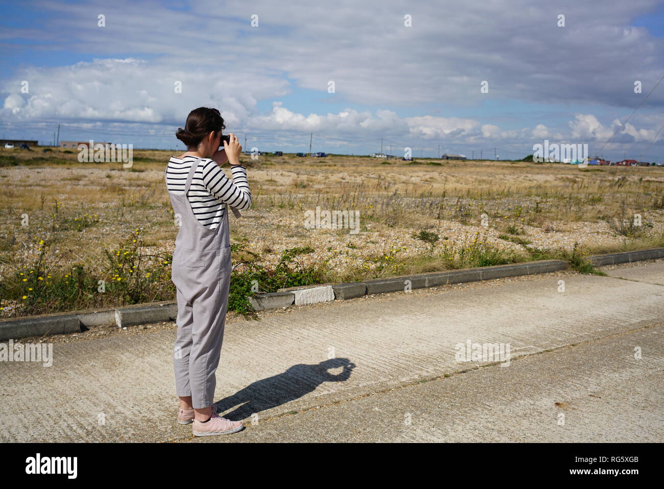 Una femmina di fotografo nella Dungeness paesaggio. Foto Stock