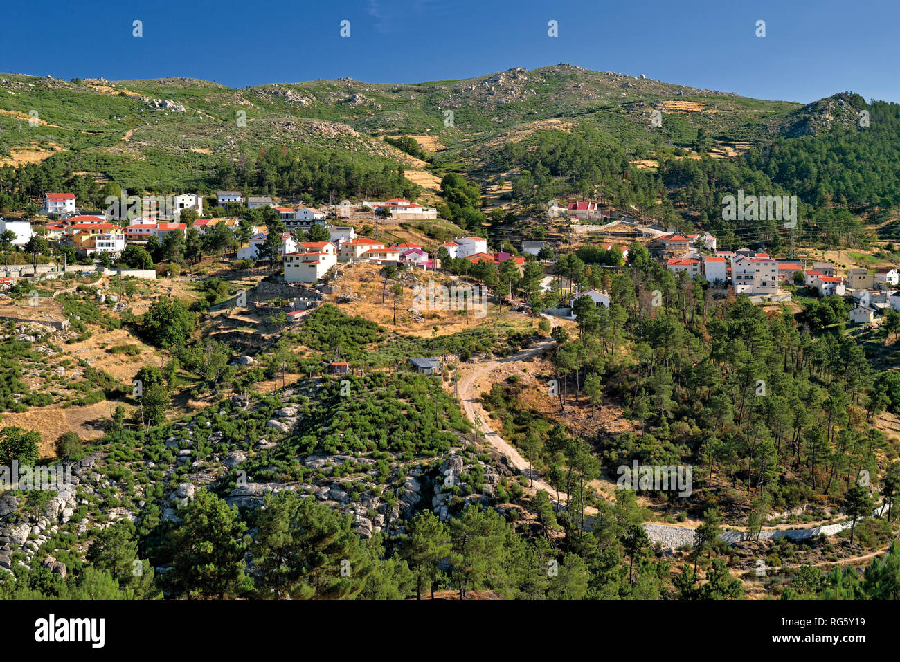 Vista del villaggio di montagna circondato da montagne verdi e rocce Foto Stock