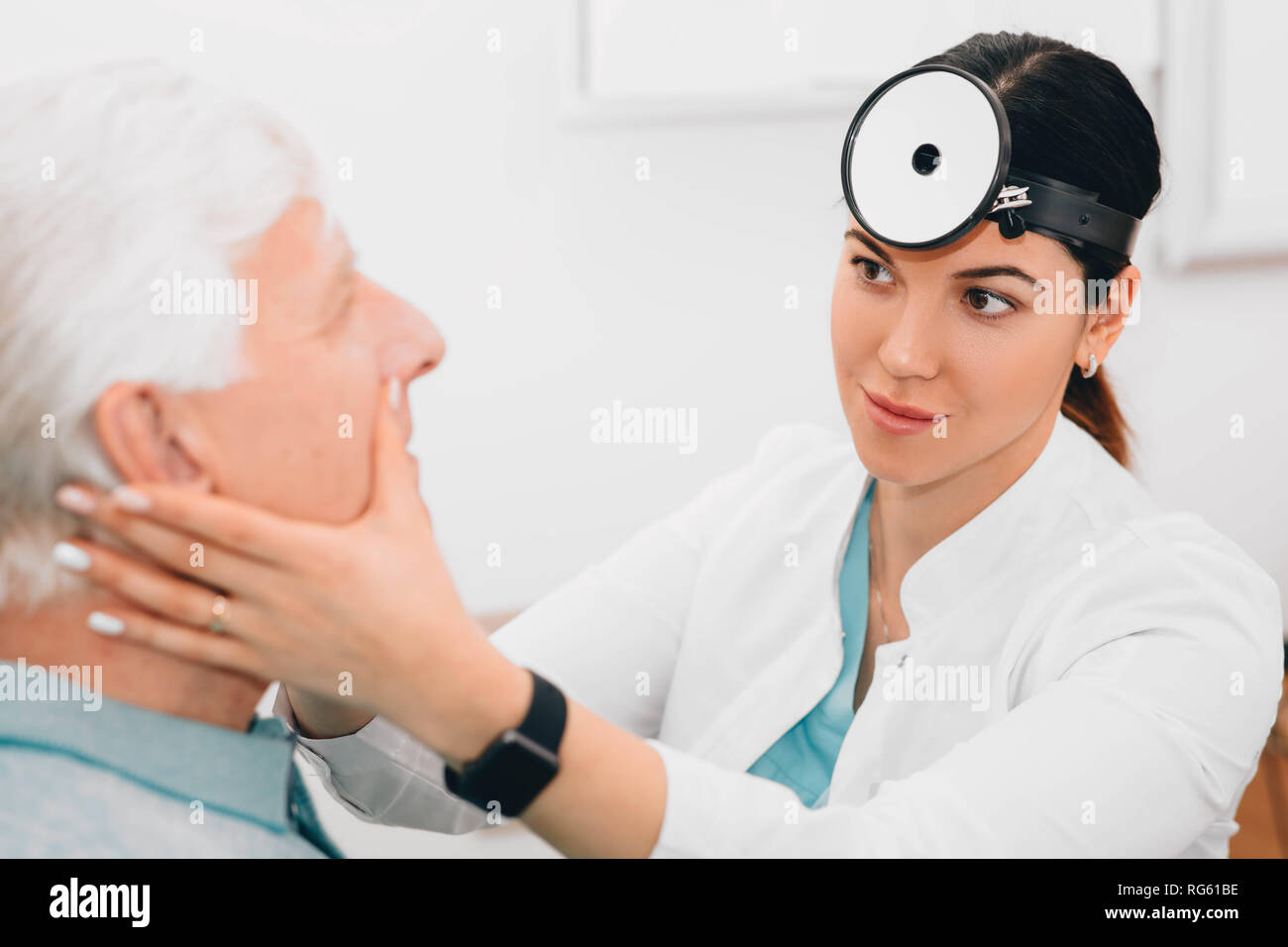 Medico otolaryngologist esaminando il suo paziente, controllare gli anziani uomo naso alla clinica Foto Stock