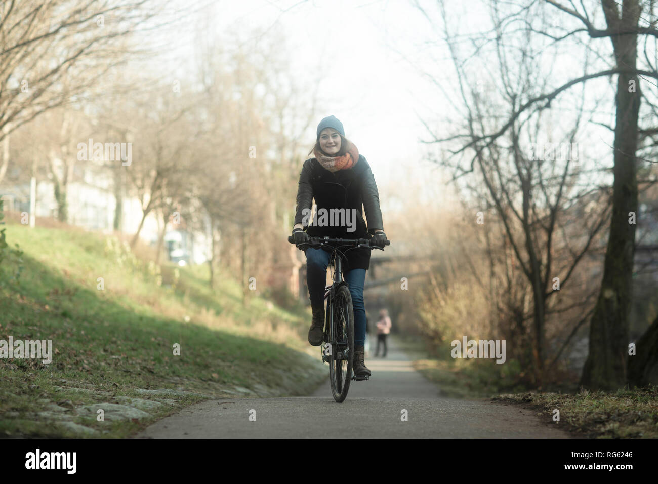 Donna in bicicletta lungo un sentiero lungo il fiume, Germania Foto Stock