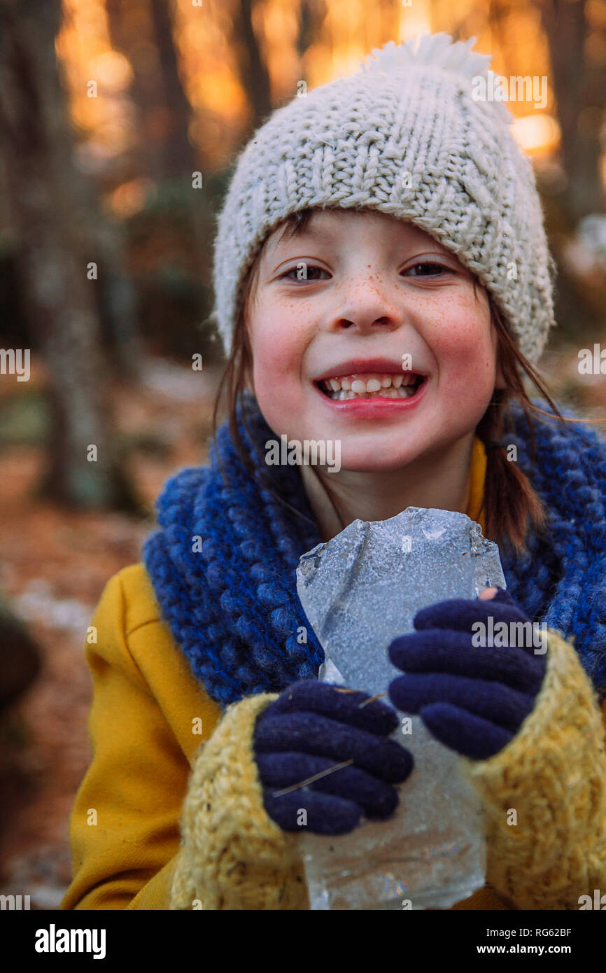 Ragazza sorridente in piedi nella foresta tenendo un pezzo di ghiaccio, Stati Uniti Foto Stock