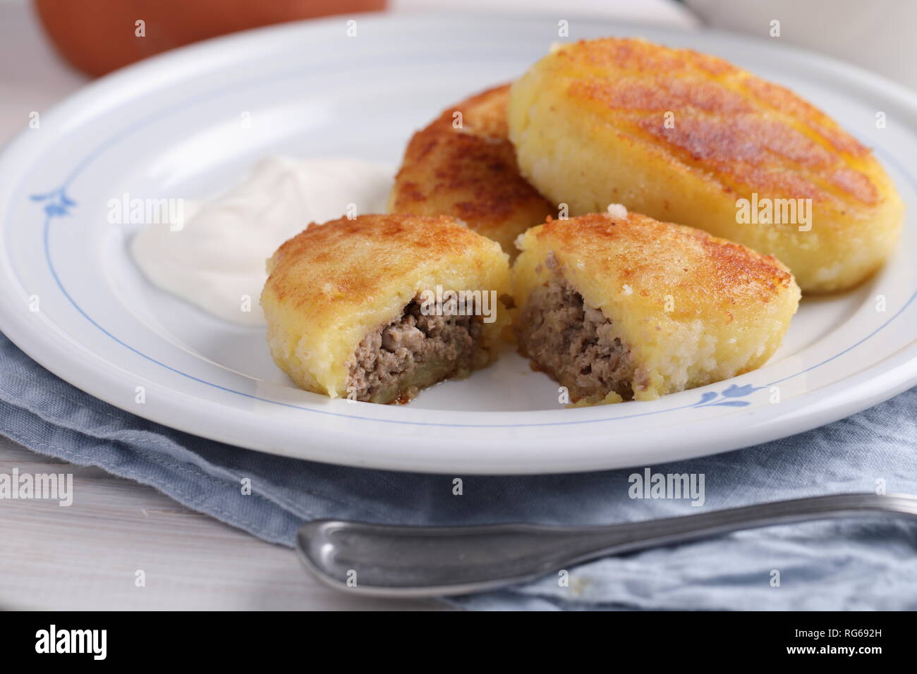 Carni di patate polpette di riempimento con panna acida su un tavolo rustico Foto Stock