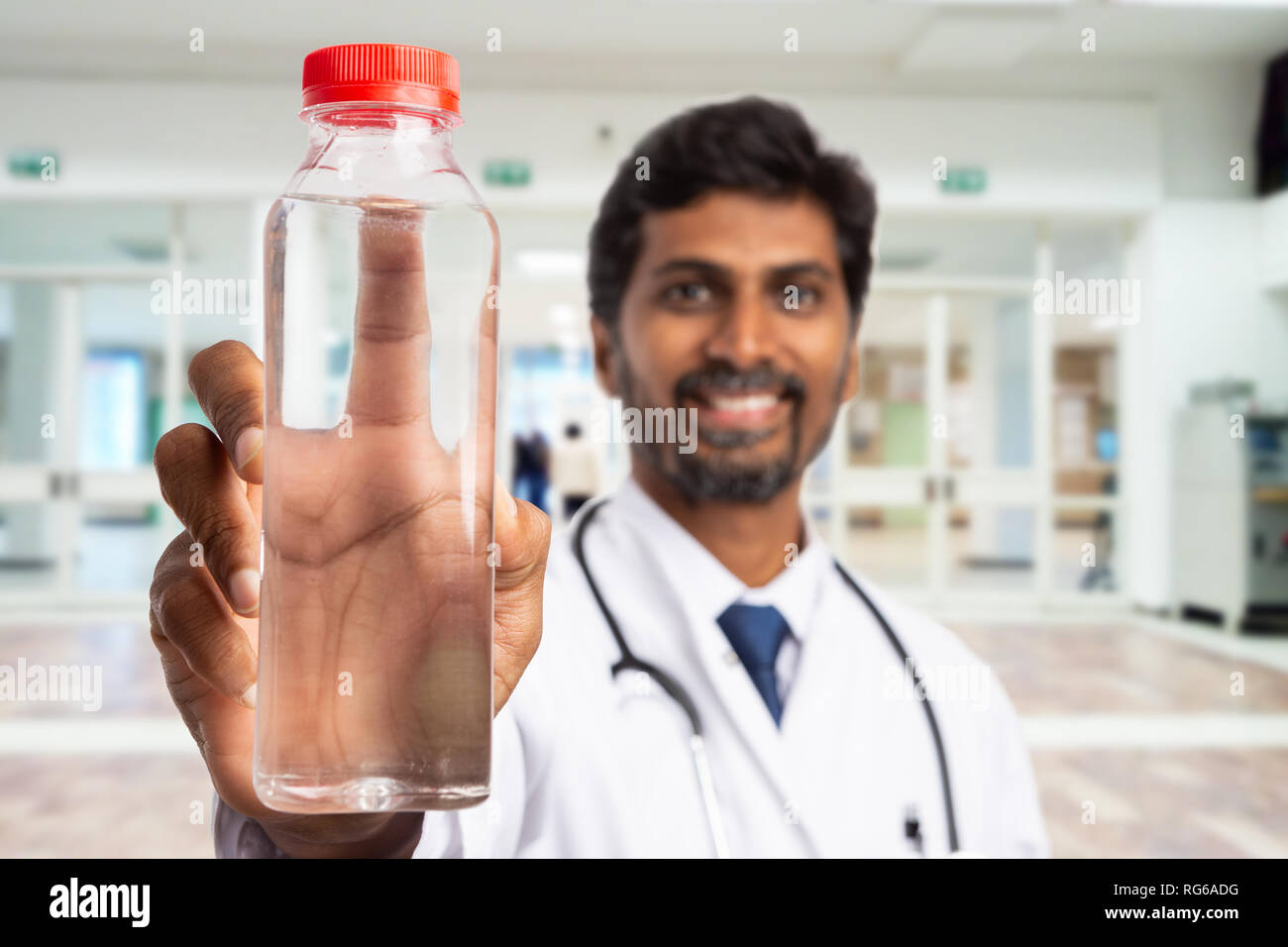 Close-up di bottiglia d'acqua in plastica detenute da indian medic o medico con il fuoco selettivo come importante mantenere idratato concept Foto Stock