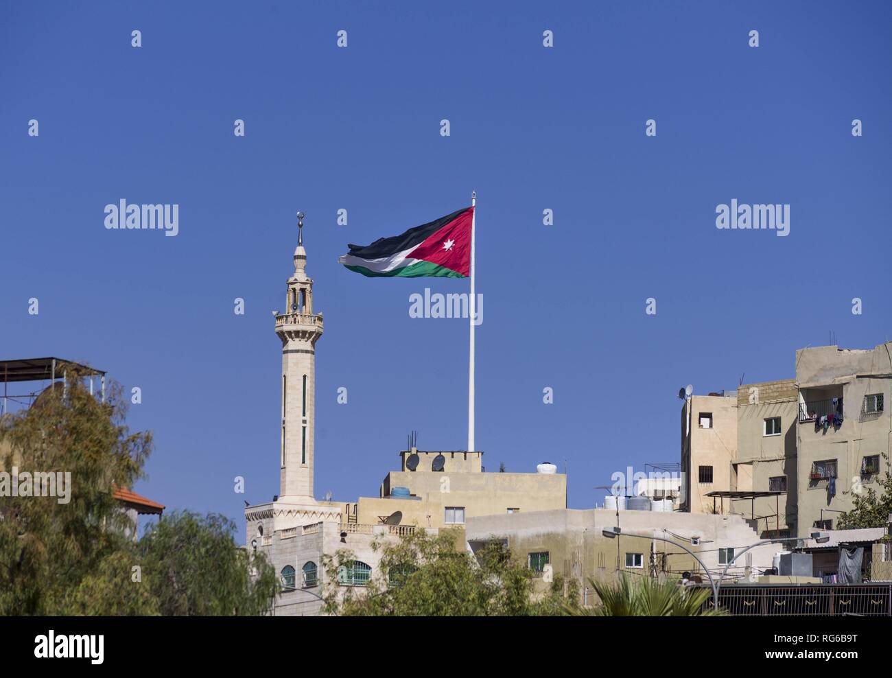 Proprio accanto a un minareto della Giordania bandiera nazionale sembra flutter sopra la città vecchia di Amman. Infatti i 1.800 metri quadrati bandiera gigante si trova su di un misuratore di 126.8 montante di alta. (02 novembre 2018) | utilizzo in tutto il mondo Foto Stock
