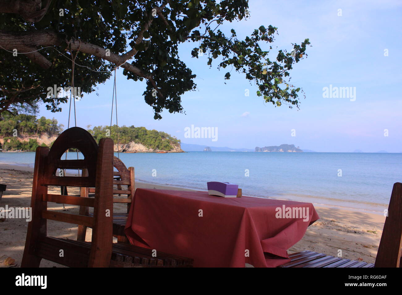 Tisch und Stühle am Strand einer thailändischen Insel mit Ausblick aufs Meer und die umgebenden isole Foto Stock