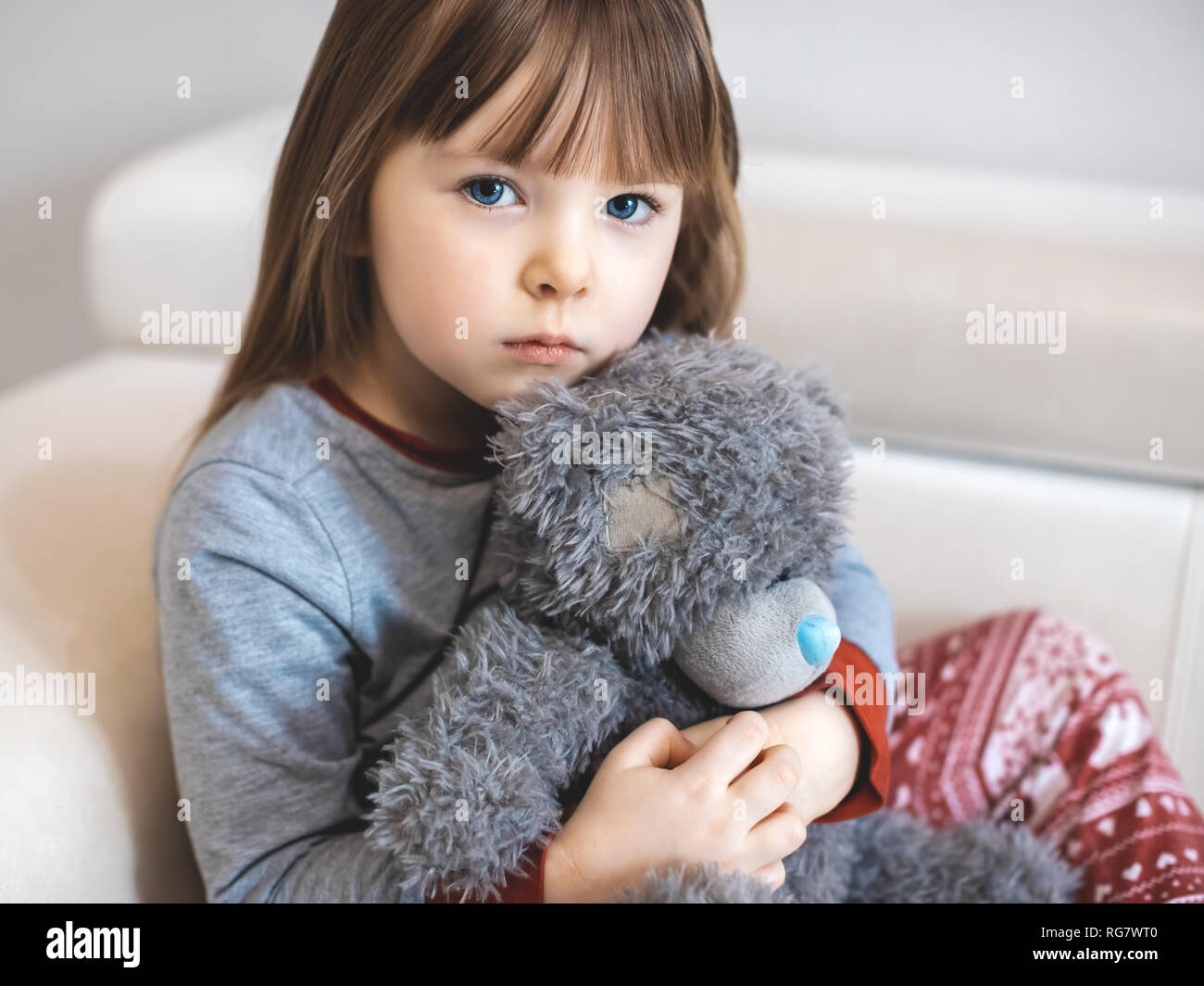 Ritratto di bambina. Kid faccina triste seduto da solo in camera. Foto Stock