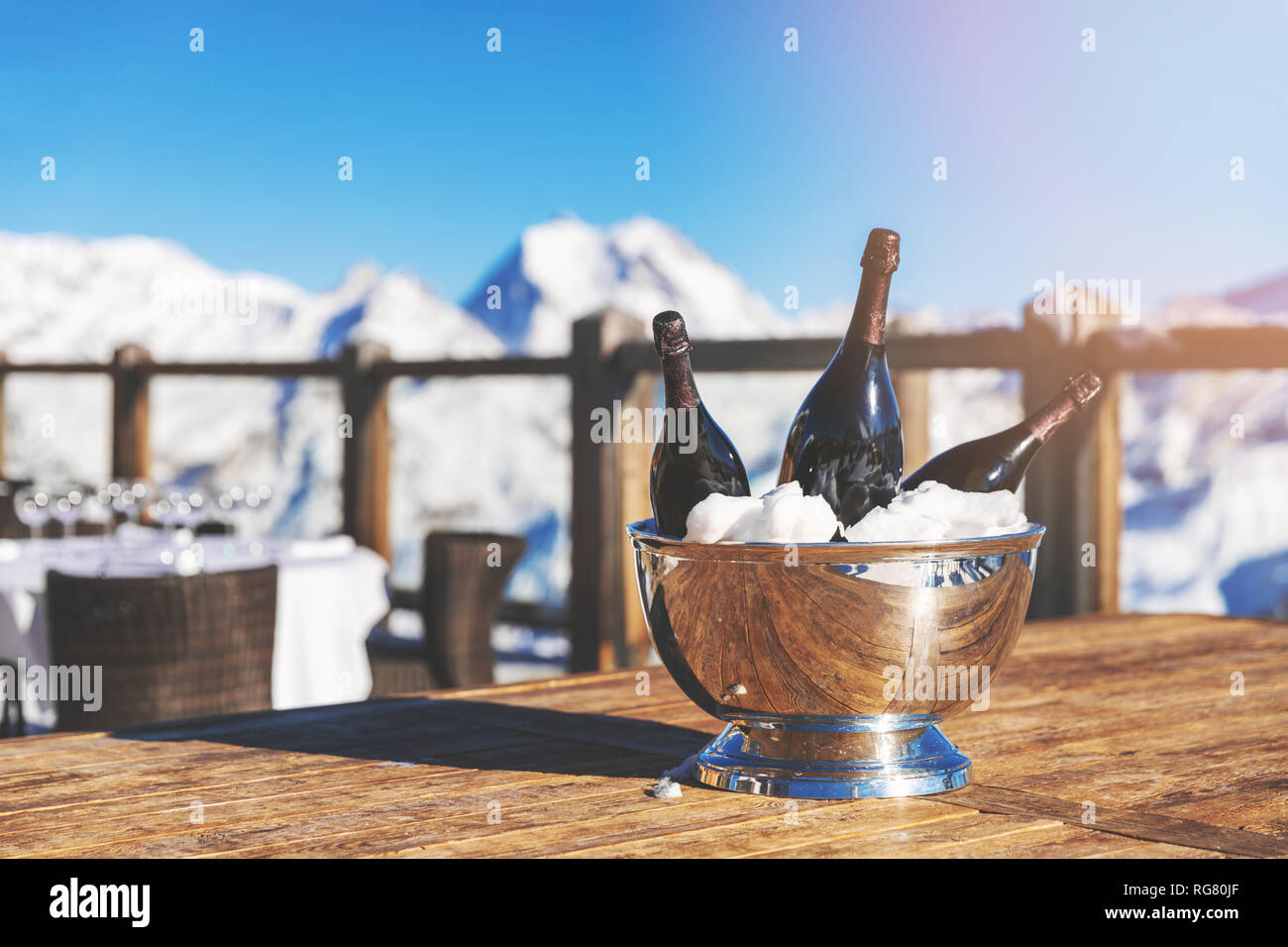Benna con bottiglie di champagne sul tavolo ristorante contro la montagna innevata sullo sfondo Foto Stock