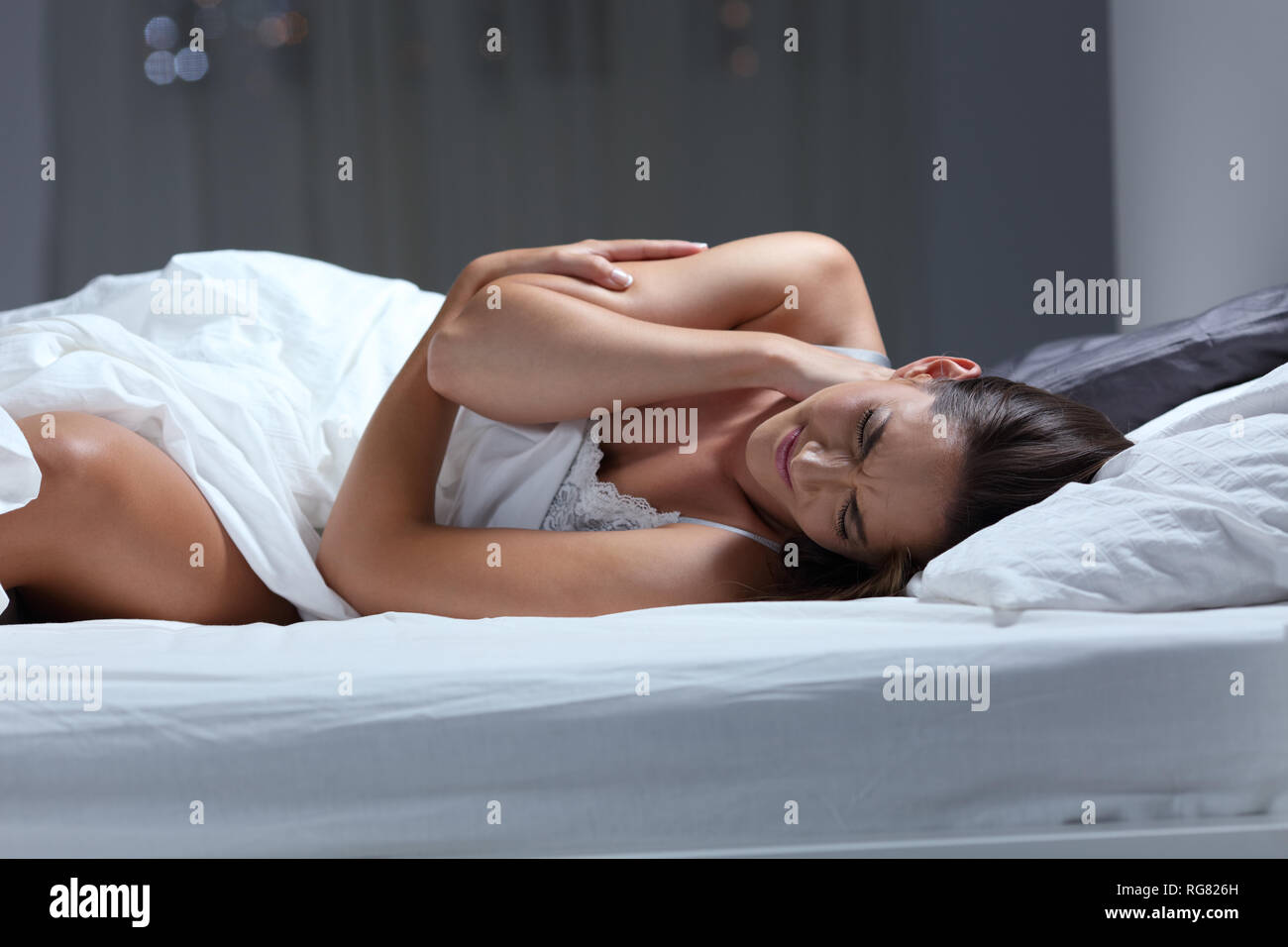 La donna lamenta sofferenza mal di collo dorme con un cuscino male su un letto di casa Foto Stock