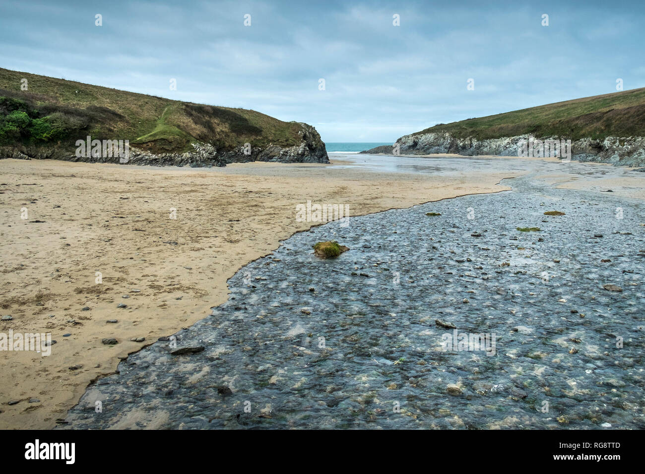 Un piccolo fiume che scorre attraverso la spiaggia con la bassa marea presso l'appartato Polly Porth scherzo cove in Newquay Cornwall. Foto Stock