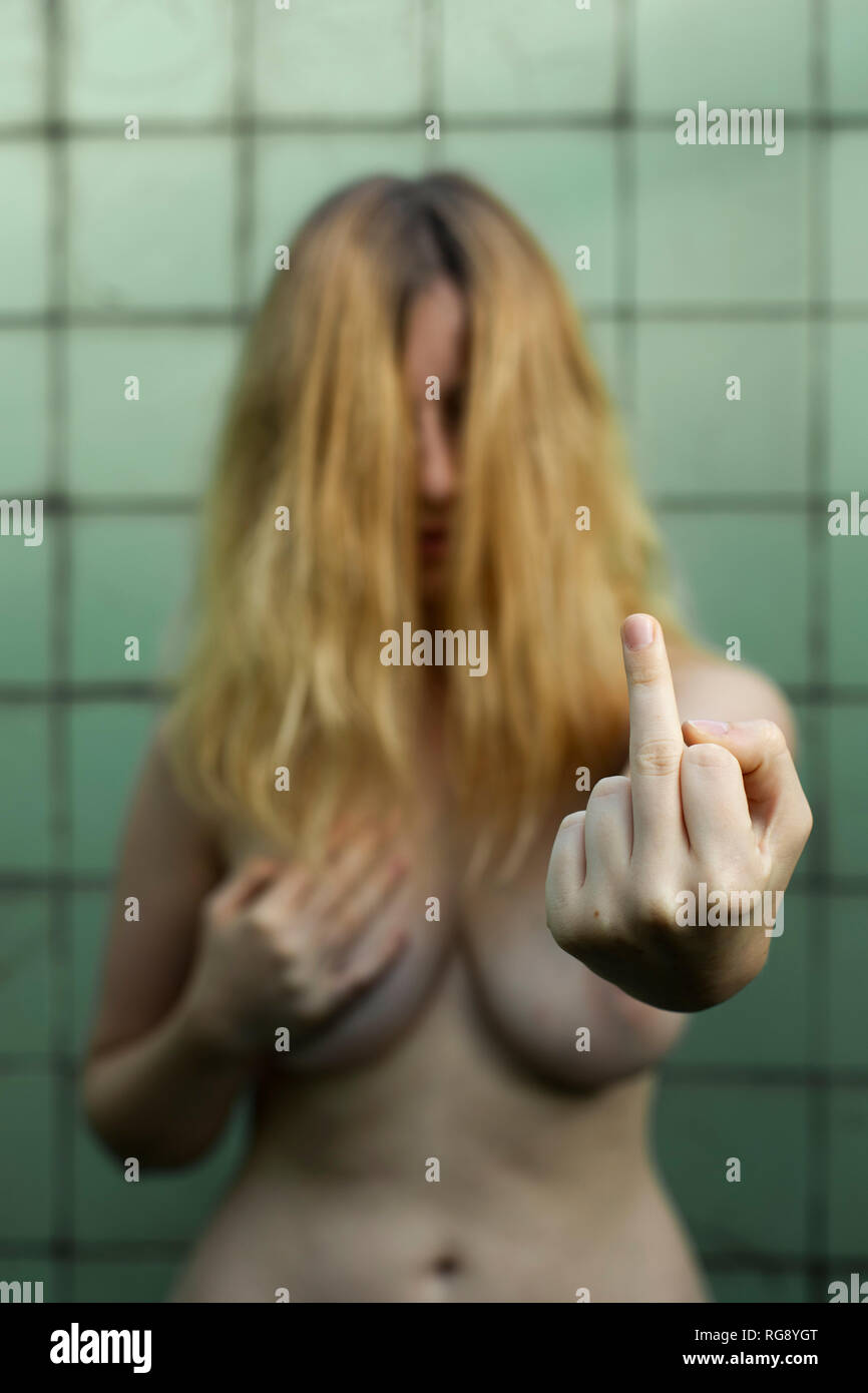 Nudo di donna mostrare le emozioni in bagno, il femminismo, abuso e la violenza contro le donne, dando il dito Foto Stock
