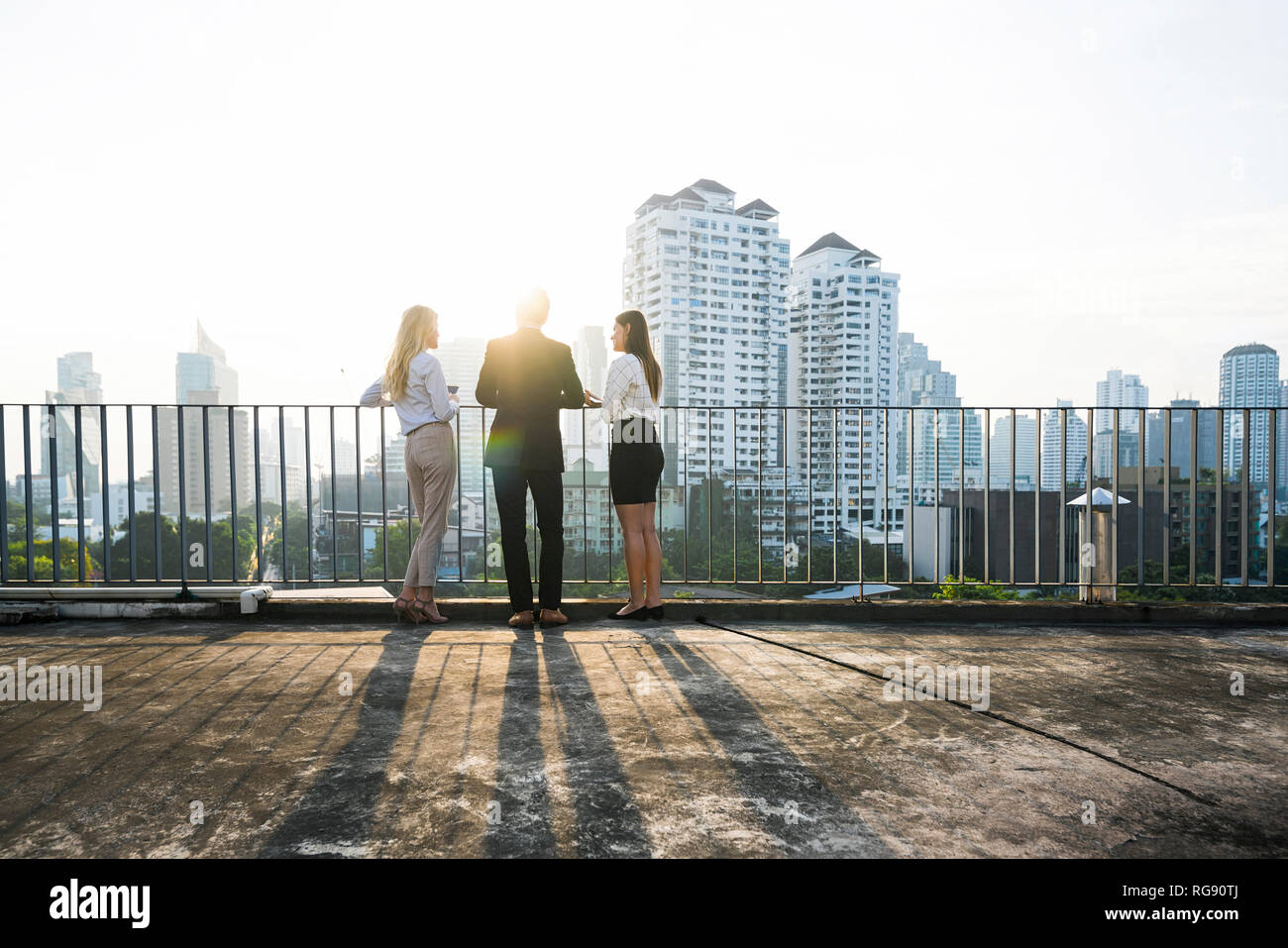 I colleghi in chat con il tramonto sul tetto della città Foto Stock