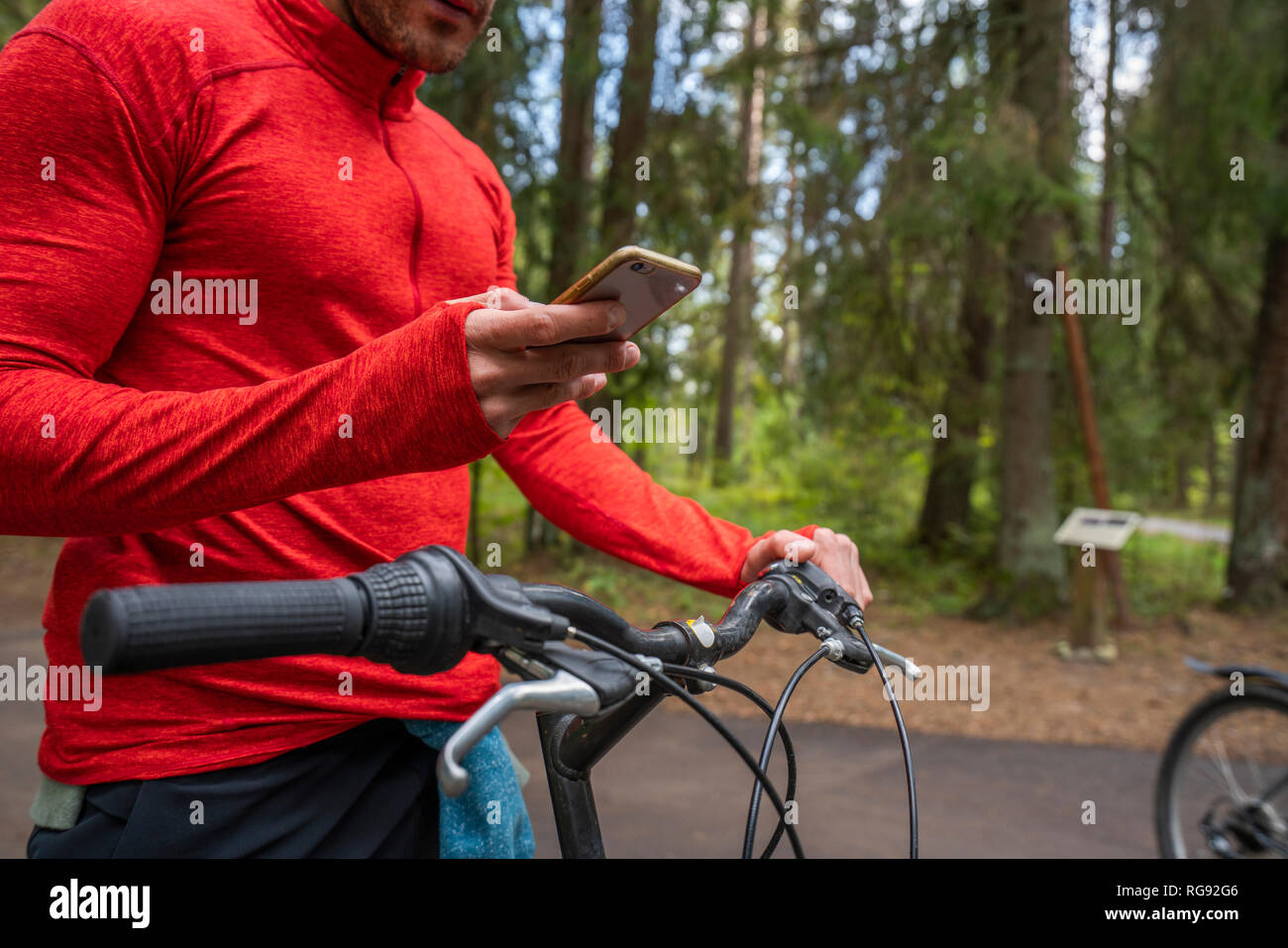 Mountain Biker utilizza lo smartphone in una foresta Foto Stock