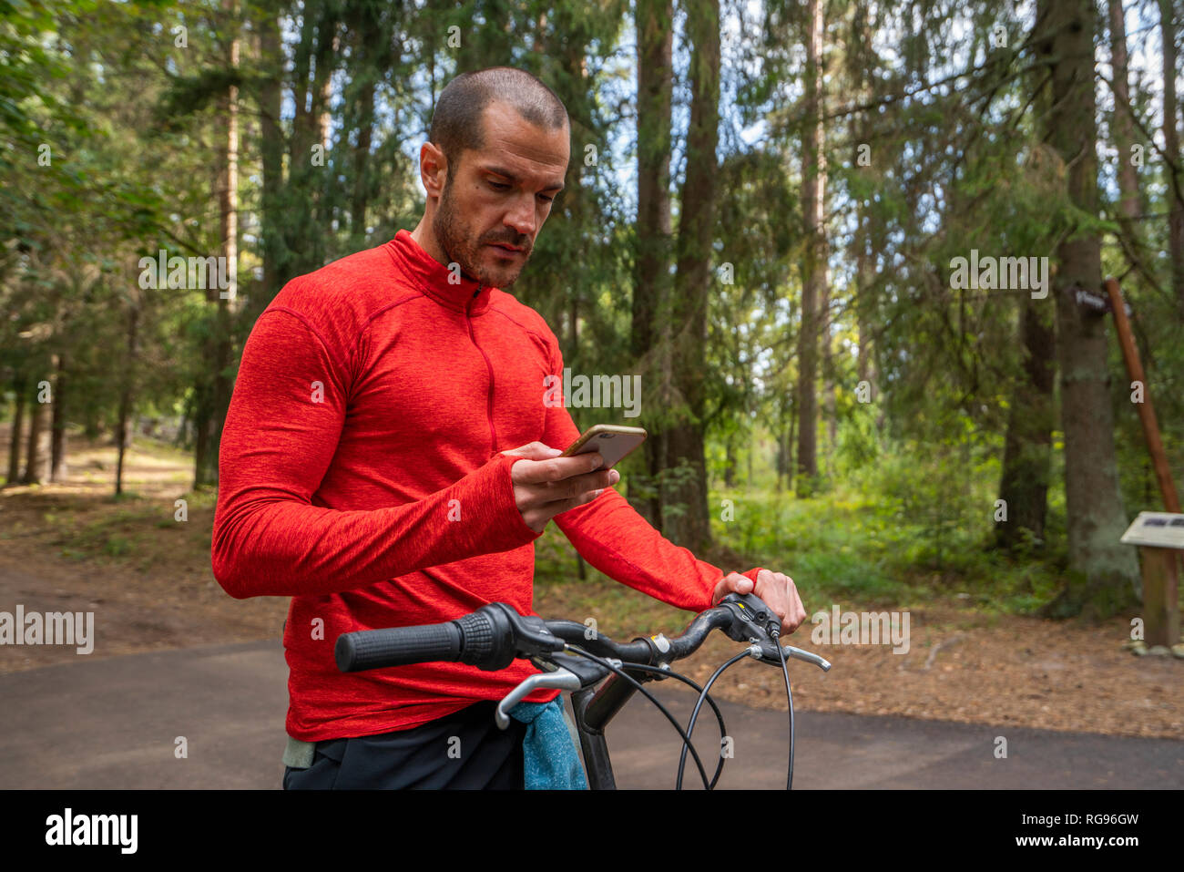Mountain Biker utilizza lo smartphone in una foresta Foto Stock