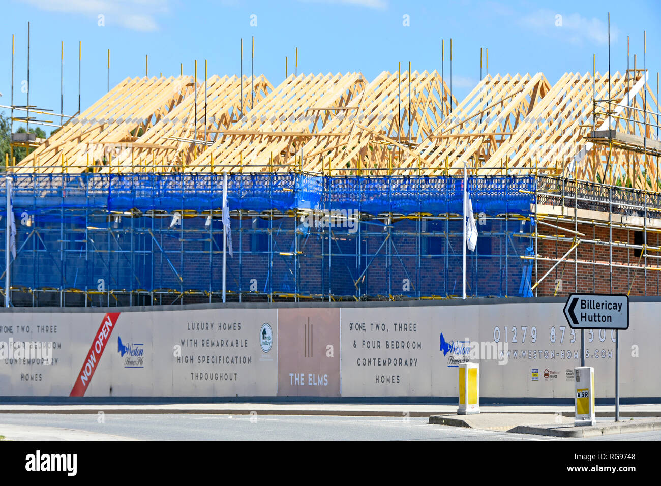 Tetto di legno & ponteggio house edificio di sviluppo del sito di costruzione di nuove abitazioni con aiuto per acquistare home logo sulla palizzata Brentwood Essex England Regno Unito Foto Stock