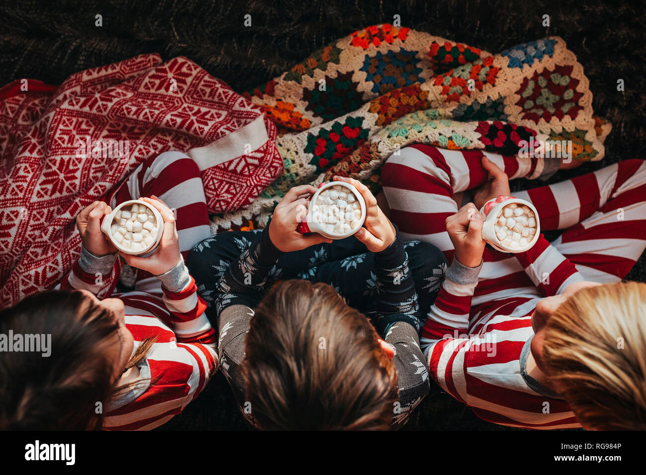Tre bambini seduti su un lettino di bere cioccolata calda Foto Stock