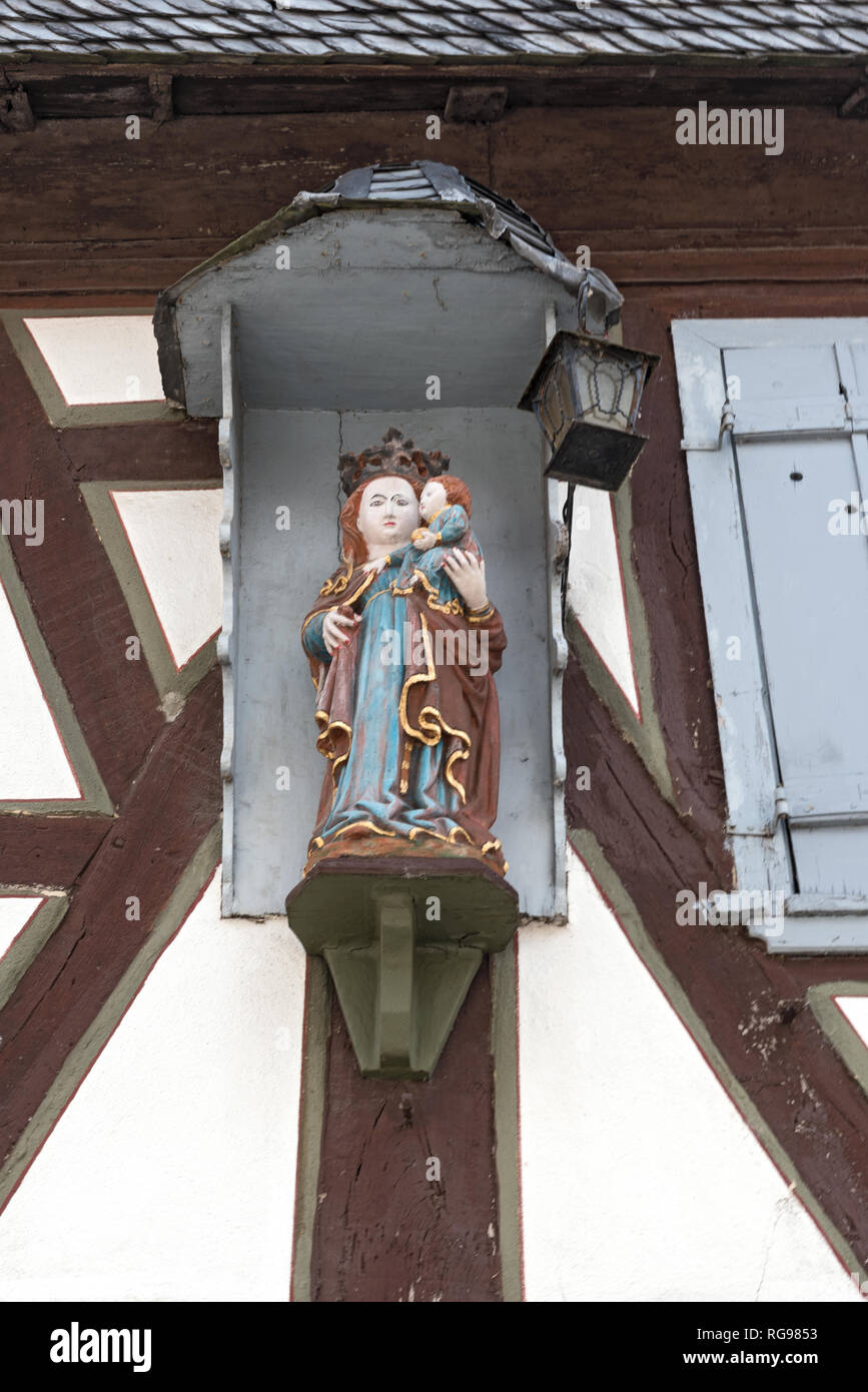 La statua della Vergine Maria e Gesù i ragazzi sulla parete esterna di una vecchia casa in legno e muratura Foto Stock